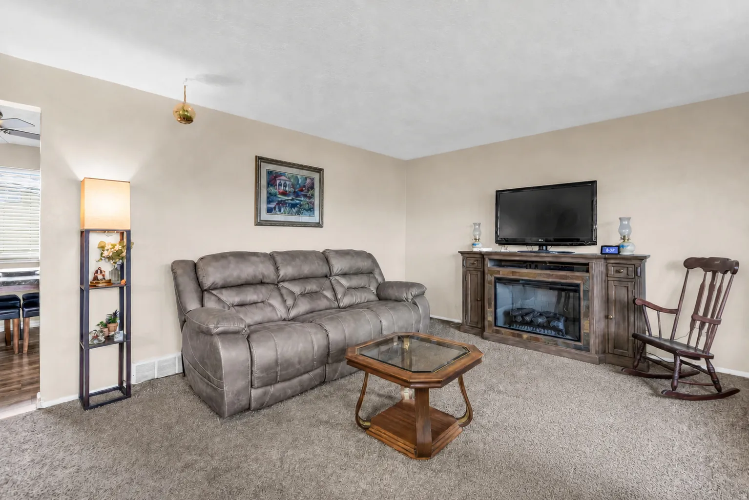 Carpeted living area featuring a built-in electric fireplace and light-colored walls