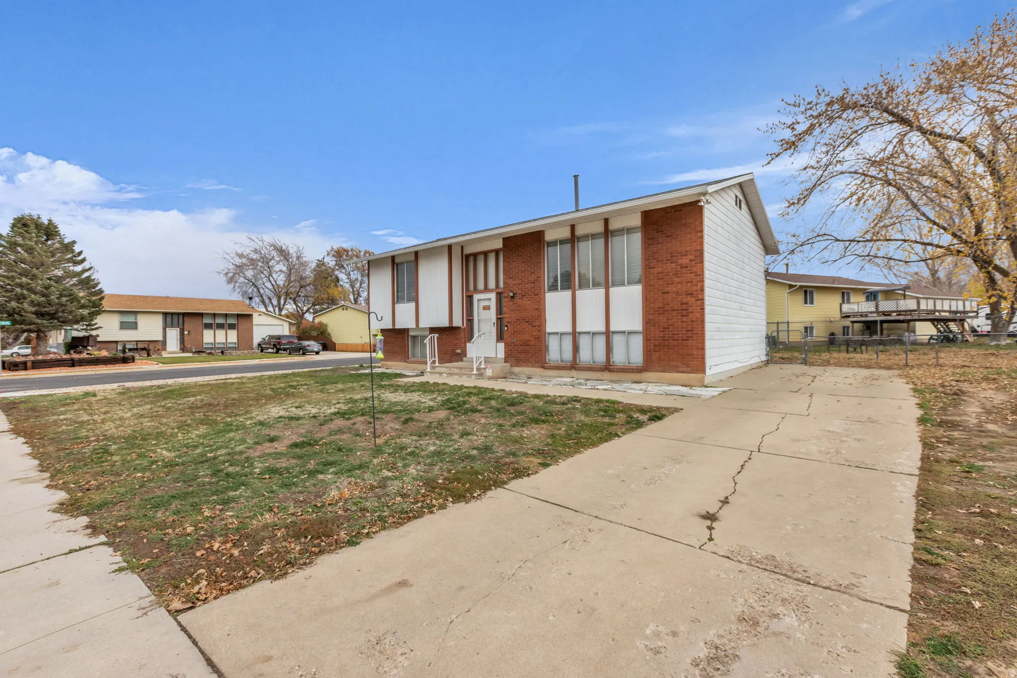 Split-level residence featuring a brick and siding exterior, a front entry with a small porch, and a concrete driveway