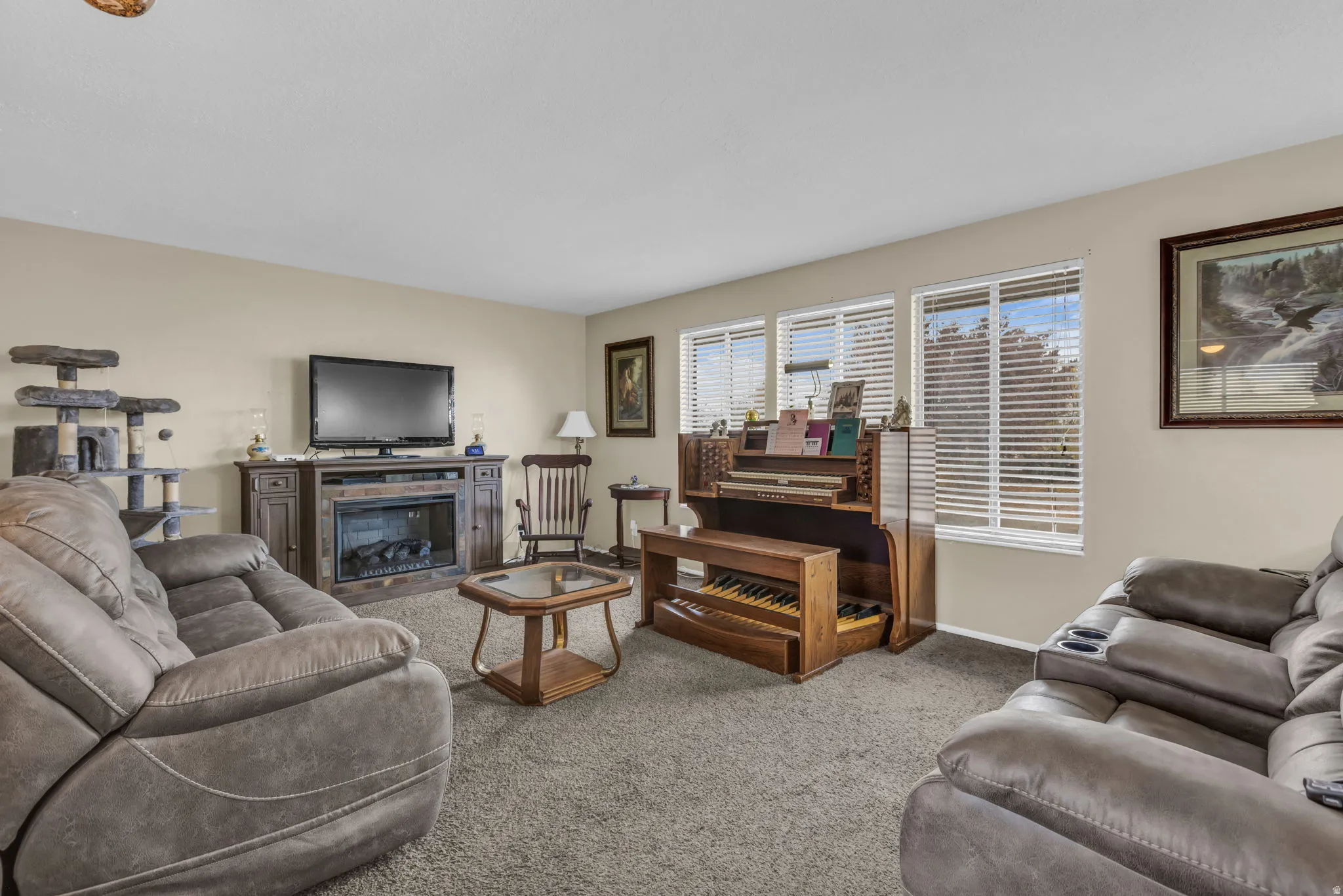 Living area featuring light beige walls, multiple windows with blinds, and carpet flooring