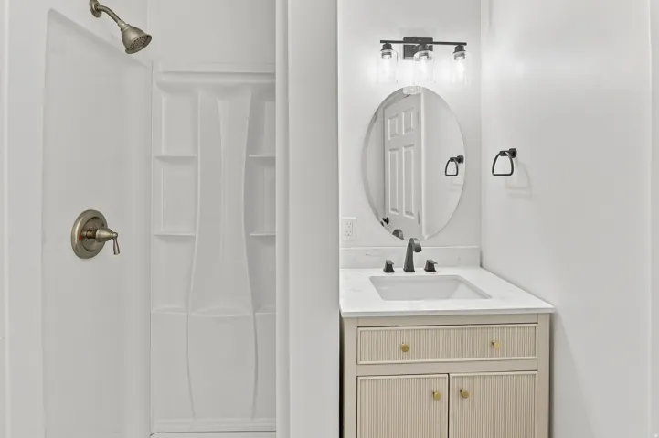 Contemporary bathroom featuring a light-toned vanity with textured cabinet doors, a white integrated sink, and a contrasting dark-finish faucet
