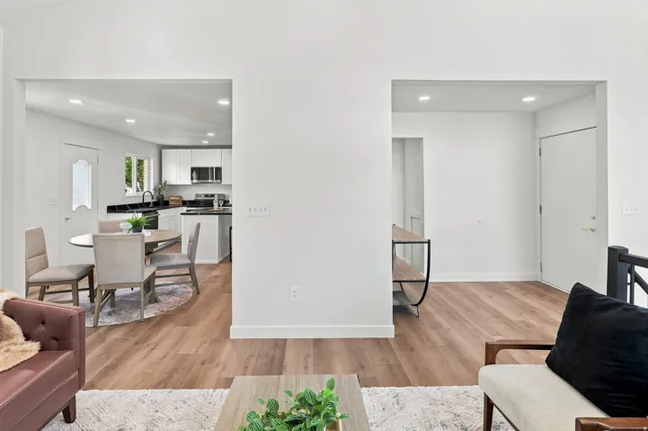 Open-concept living area featuring wood-finish flooring, recessed lighting, and crisp white walls