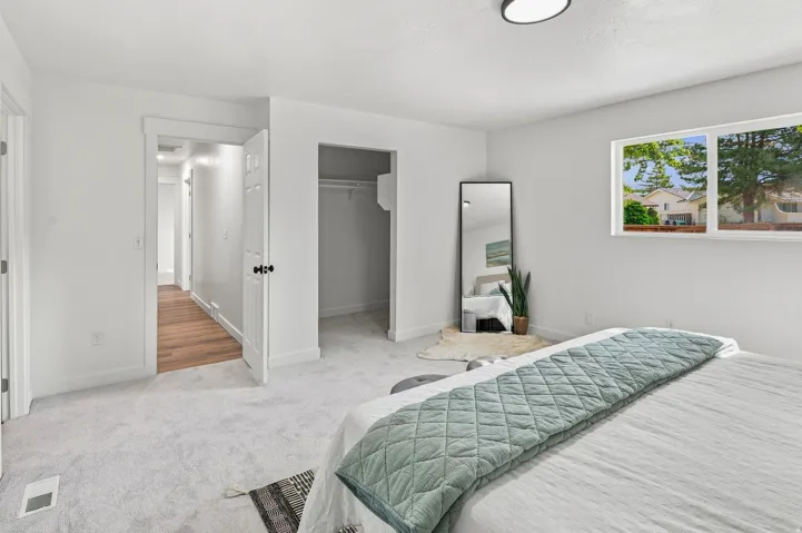 Spacious room featuring light gray carpeting, a window with exterior views, and a closet with shelving