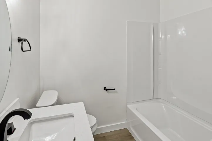 Modern bathroom featuring a white vanity with an integrated sink, black faucet, and a large round mirror