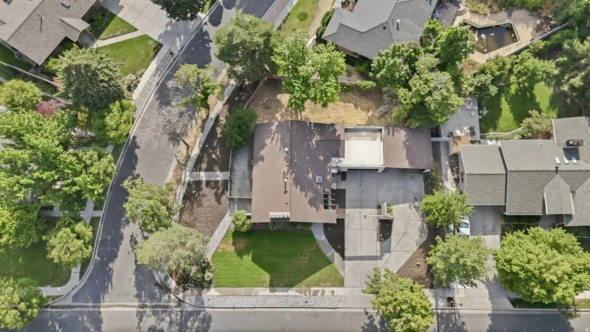 Property featuring a brown shingle roof, a paved driveway, and mature landscaping