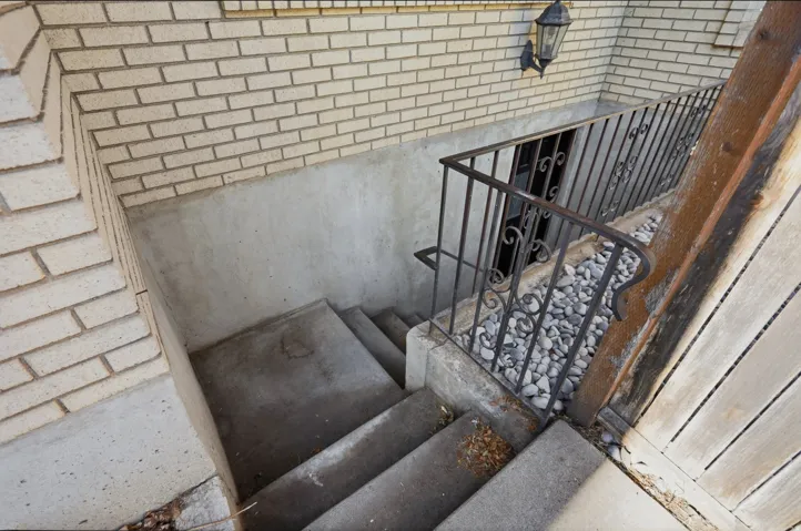 Exterior concrete stairwell with a wrought iron handrail, leading to a recessed entry