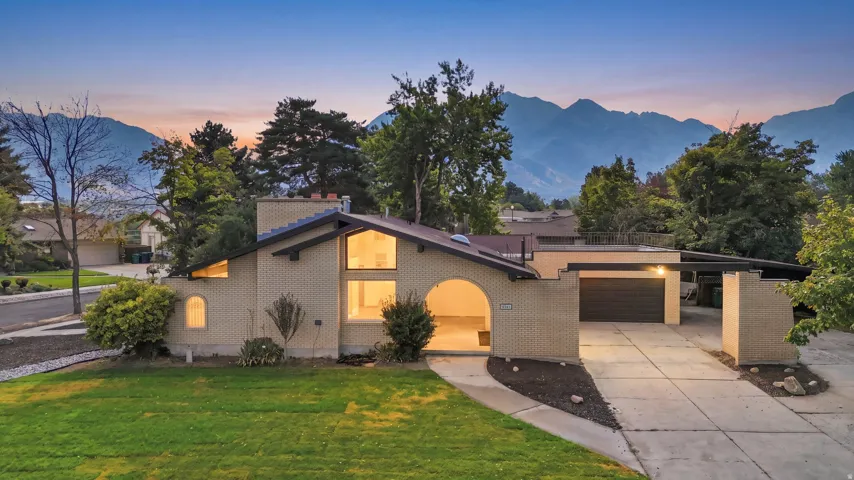 Contemporary brick exterior featuring a vaulted roofline, prominent A-frame window configuration, an arched entry, a two-car garage, and a concrete driveway