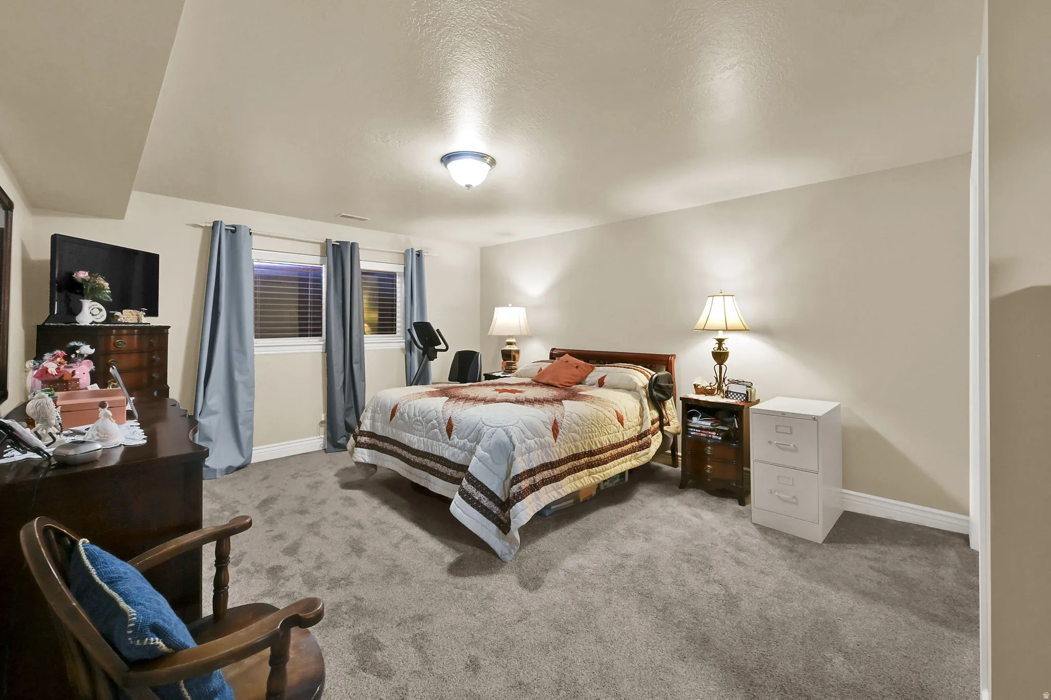 Spacious room featuring neutral-toned walls, gray carpeting, and  windows with blinds