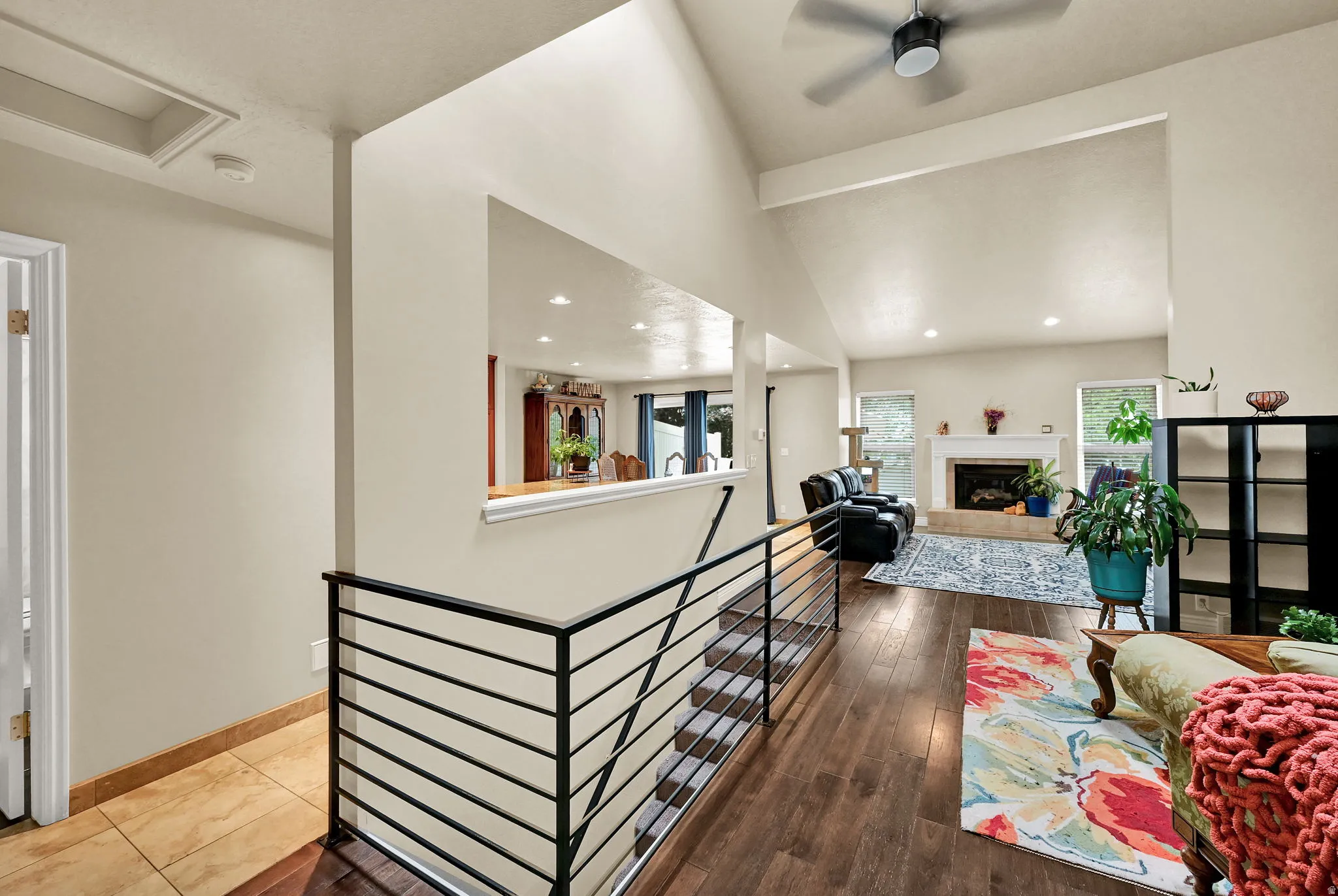 Vaulted ceiling living area with a fireplace and wood-finish flooring