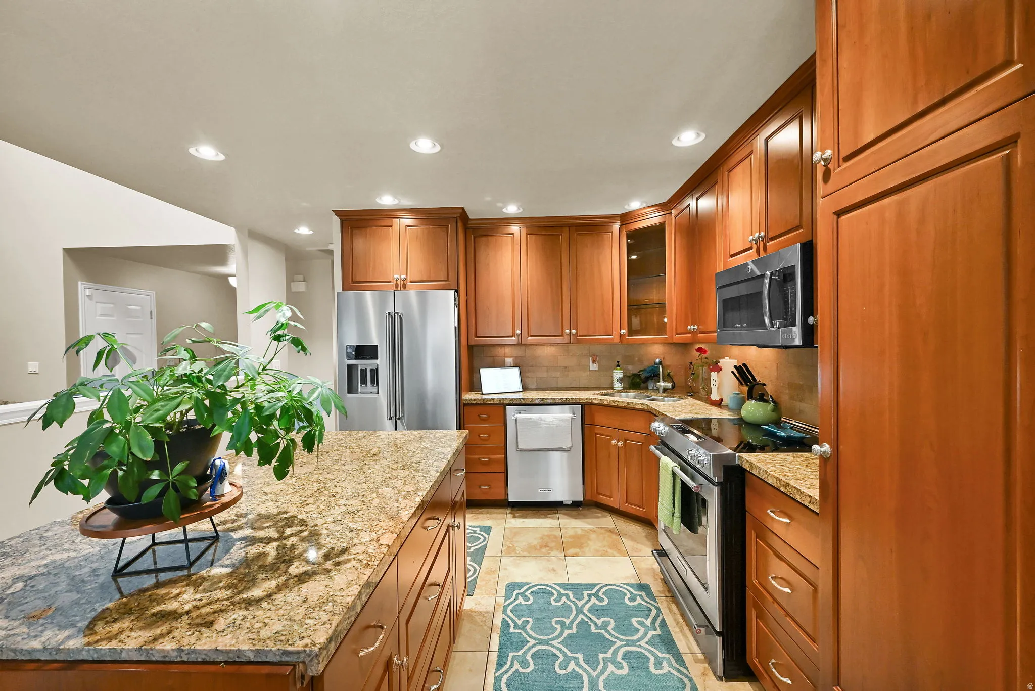 Kitchen featuring wood cabinetry, stainless steel appliances, recessed lighting, and stone countertops
