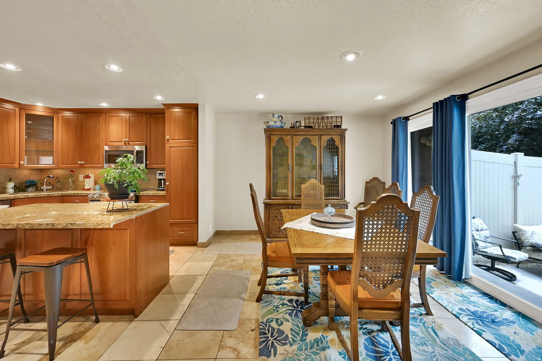 Kitchen and dining area featuring wood cabinetry, an island with stone countertop, stainless steel appliances, and recessed lighting