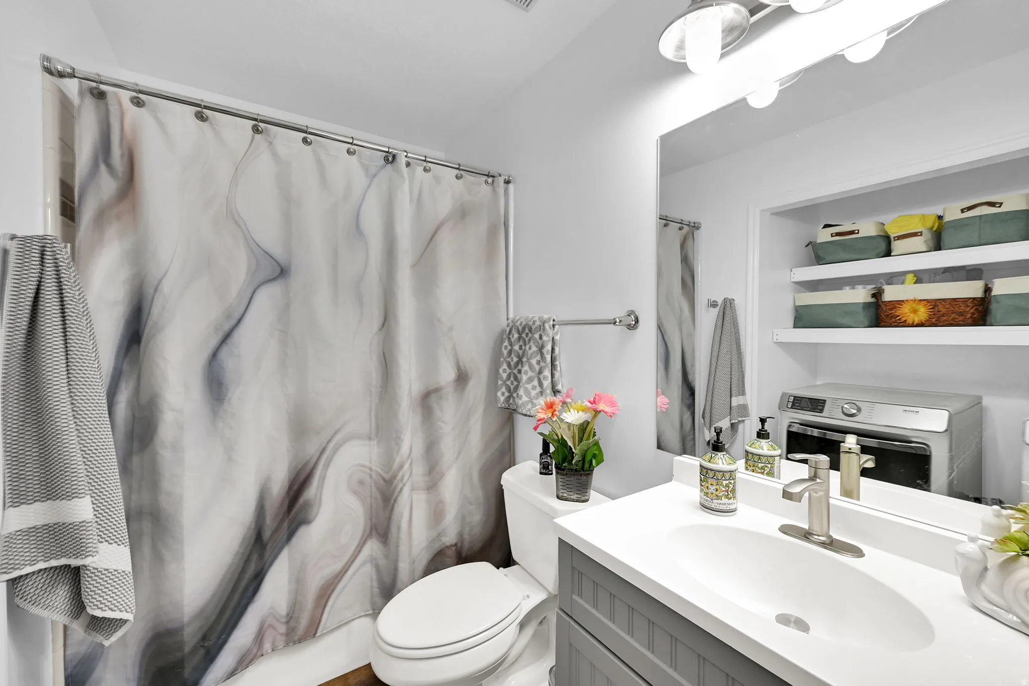 Full bathroom featuring a shower-tub combination, a single vanity with a white countertop, a toilet, and recessed shelving