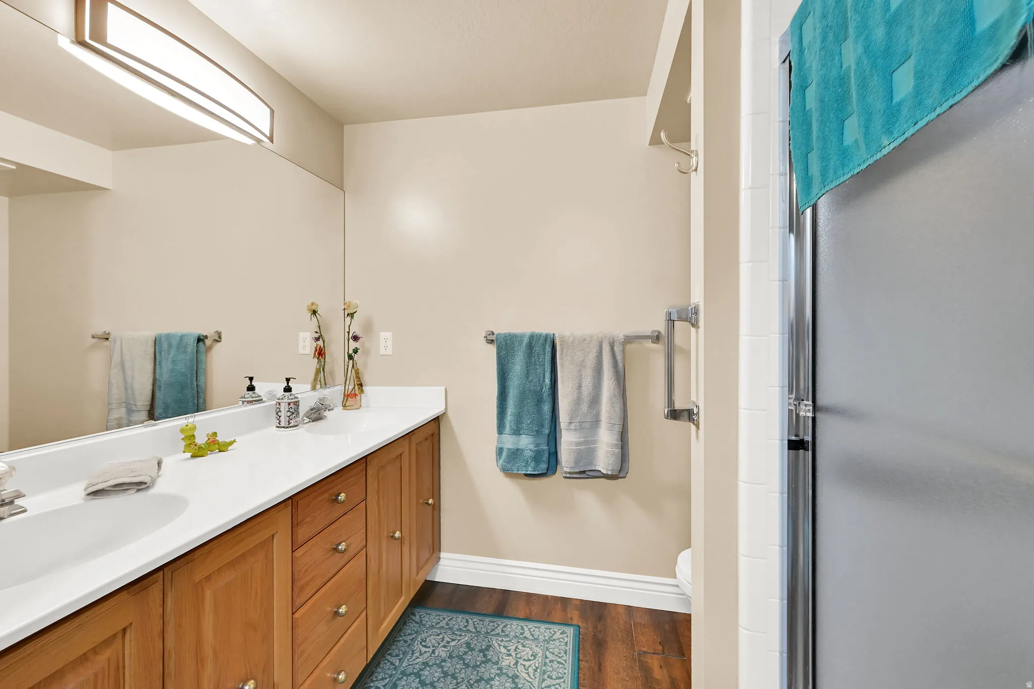 vanity with wood cabinetry, white countertop, and integrated sink