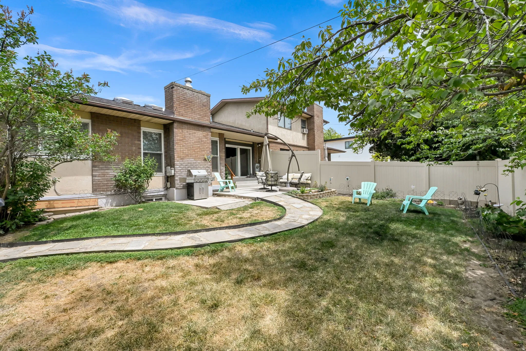 Landscaped backyard featuring a pathway, a brick and stucco exterior, and a privacy fence