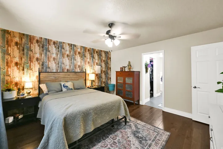 Interior room featuring a wood-finish accent wall, light-toned painted walls, and dark wood-finish flooring