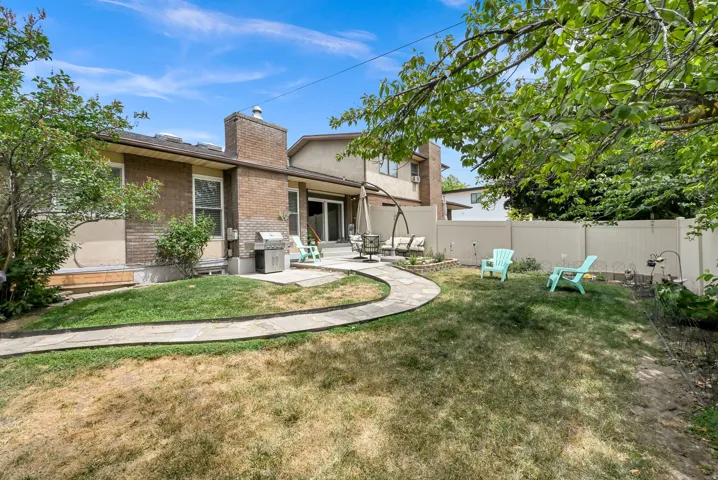 Landscaped backyard featuring a pathway, a brick and stucco exterior, and a privacy fence