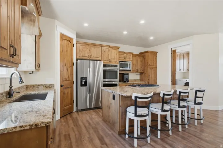 Spacious kitchen featuring wood cabinetry, stainless steel appliances, a large center island with a gas cooktop, and granite countertops