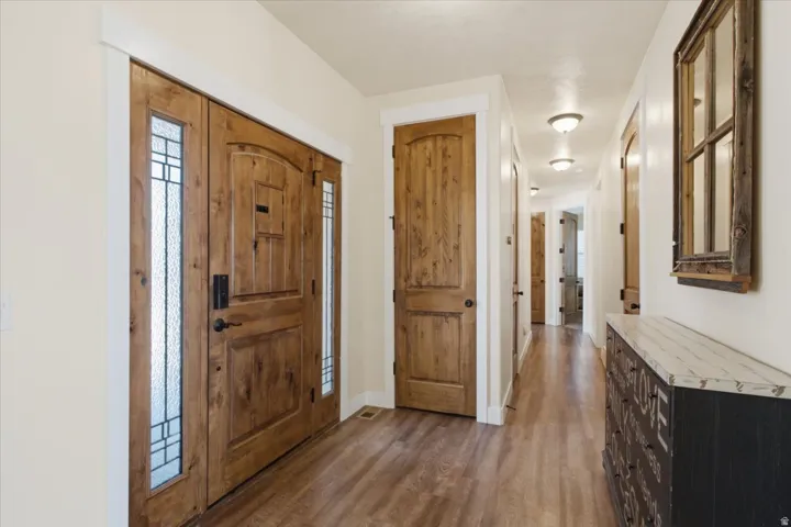 Entryway featuring a double wood-paneled door with decorative glass inserts, wood-finish flooring, and a recessed ceiling with flush-mount lighting fixtures