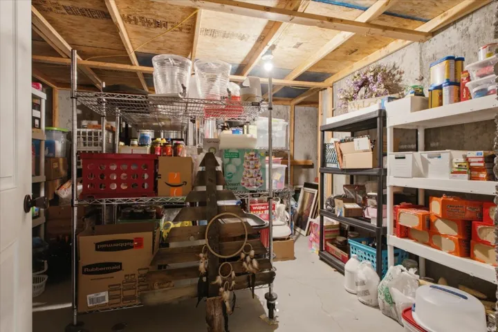Unfinished basement space featuring exposed wood joists and concrete walls, providing open storage capacity