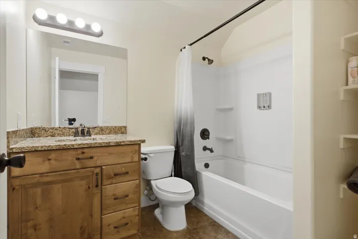 Bathroom featuring a wood-finish vanity with granite countertop, integrated sink, and bronze-finish faucet