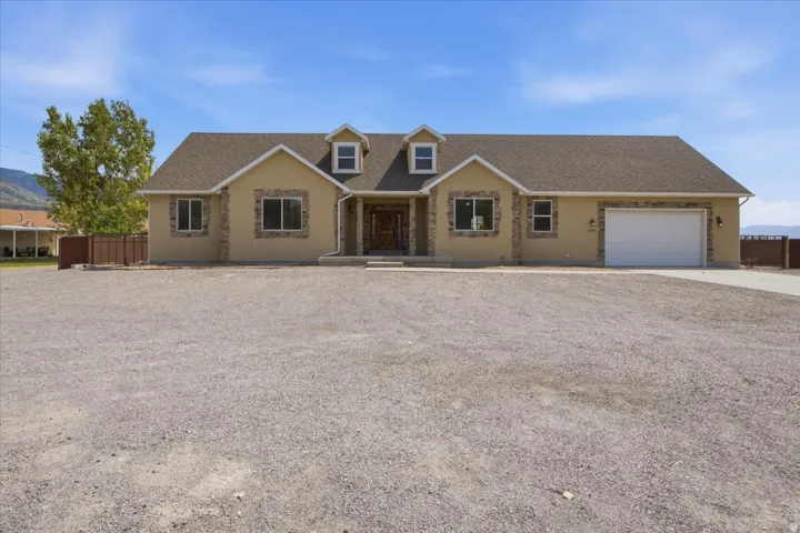 Single-story home featuring a stucco exterior with stone accents and a prominent attached garage