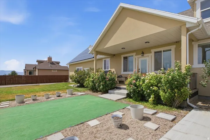 Rear exterior with covered patio, stucco finish, and solar panels