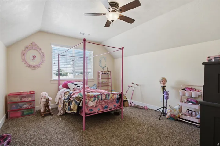 Room featuring vaulted ceilings, a ceiling fan with light fixture, neutral wall paint, and carpet flooring