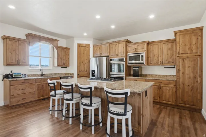 Kitchen featuring a central island, wood-finish flooring, recessed lighting, and stainless steel appliances