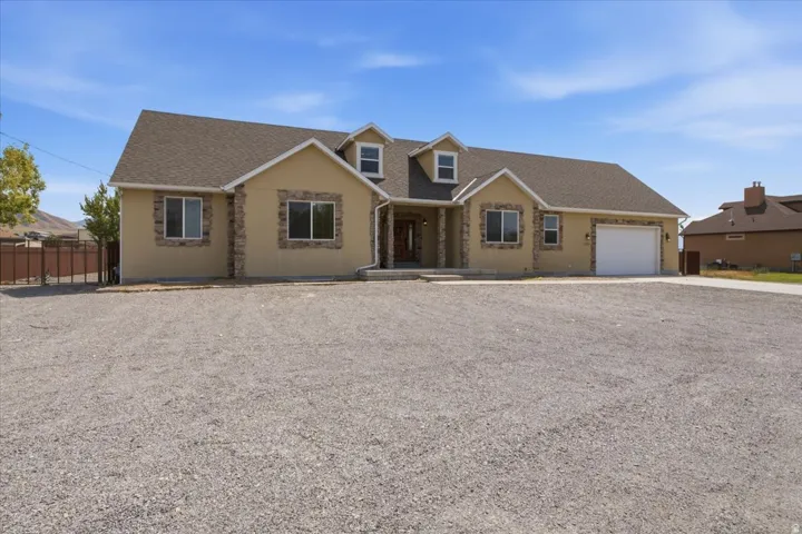 Single-story residence featuring a stucco exterior with stone accents and multiple dormer windows