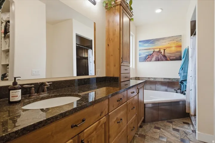 Bathroom vanity featuring an integrated oval sink, countertop with a polished finish, and bronze-toned hardware