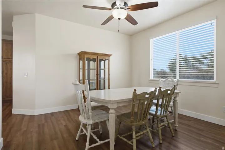 Spacious room featuring wood-finish flooring, light neutral wall paint, and a white ceiling with a built-in ceiling fan with light fixture