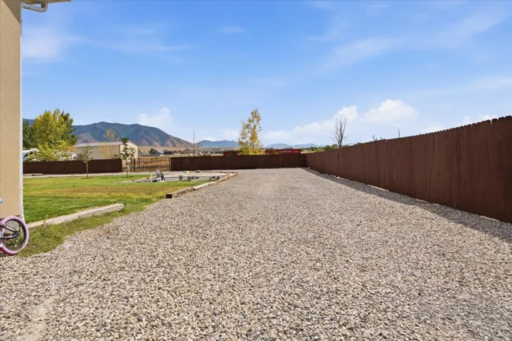 Expansive gravel driveway bordered by a tall privacy fence