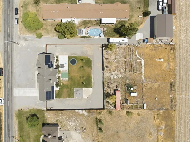 Expansive property featuring a main residence with solar panels, a detached outbuilding, and a large cultivated field