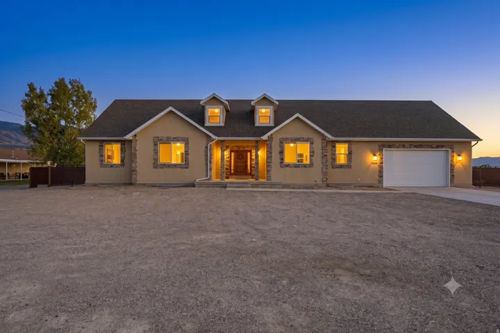 Ranch-style exterior with stone veneer accents, dormer windows, and an attached two-car garage
