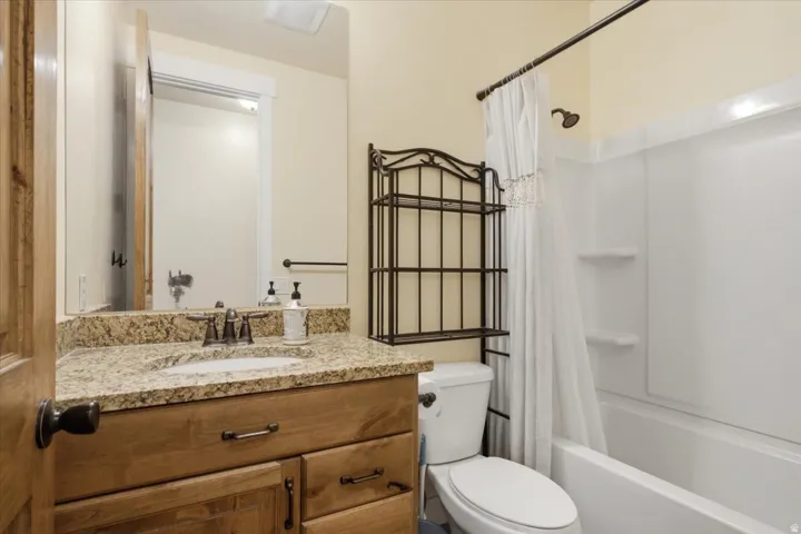 Bathroom with a light-toned wood-finish vanity, granite countertop, and integrated sink