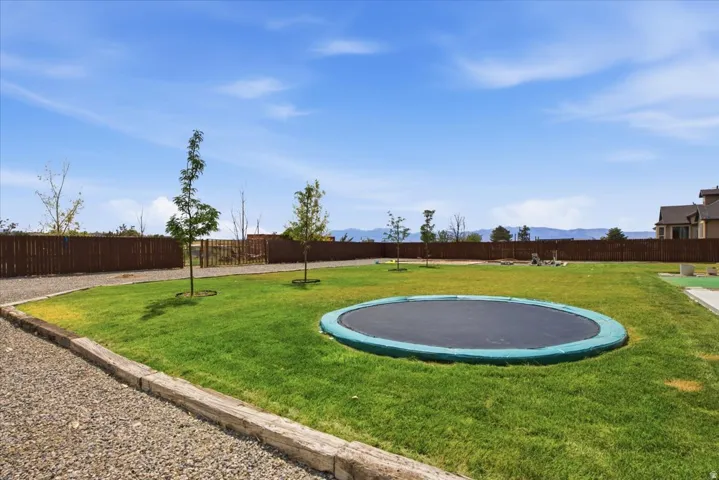 Expansive backyard featuring a manicured lawn, established trees, and a privacy fence
