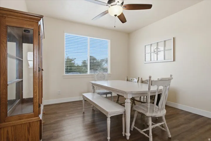 Dining area featuring wood-finish flooring, a large window with horizontal blinds, and a ceiling fan with integrated lighting
