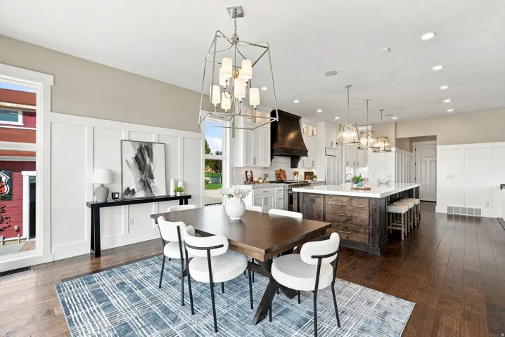 Open-concept dining area featuring wood-finish flooring, wainscoting, and a multi-light chandelier