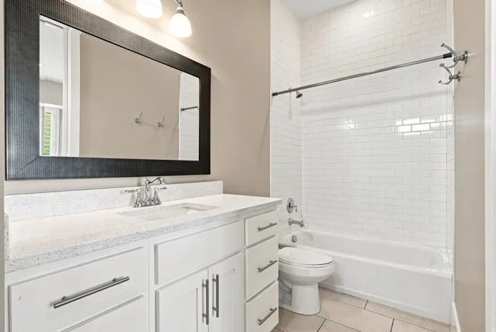 Bathroom featuring a white subway tile shower surround, a white bathtub, and a tile floor