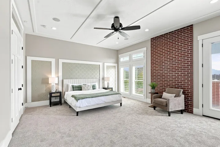 Spacious primary bedroom featuring light gray walls and a tray ceiling with recessed lighting