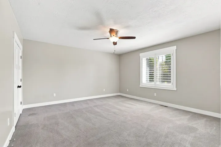 Spacious room featuring vaulted ceilings, light gray wall paint, and gray carpet flooring