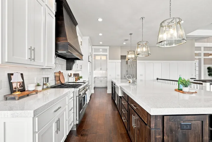 Spacious kitchen featuring white shaker cabinetry, dark wood-finish flooring, a wood-paneled range hood, and light-toned countertops