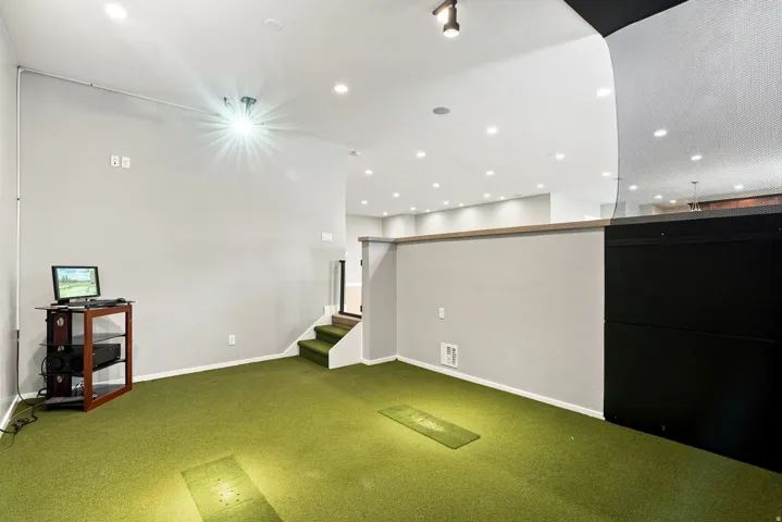 Recreational space featuring green turf flooring and recessed lighting