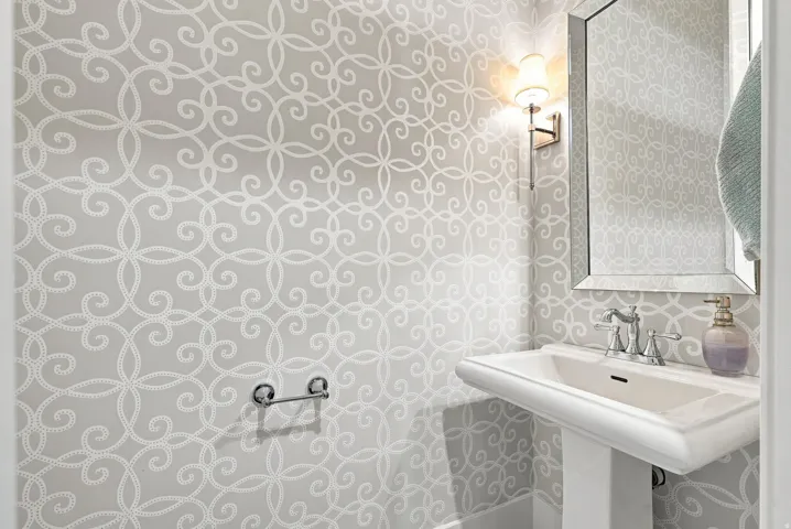 Pedestal sink with chrome faucet, mirrored vanity, and wall-mounted sconce lighting