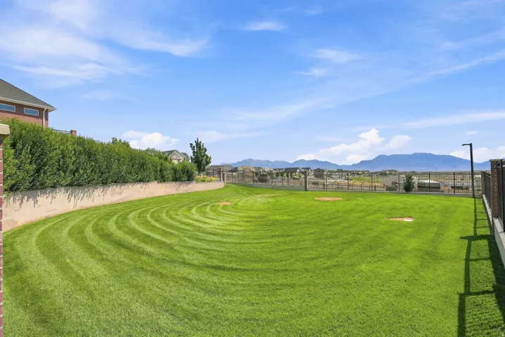 Expansive green space featuring a curved manicured lawn, a low retaining wall, and a dense privacy hedge