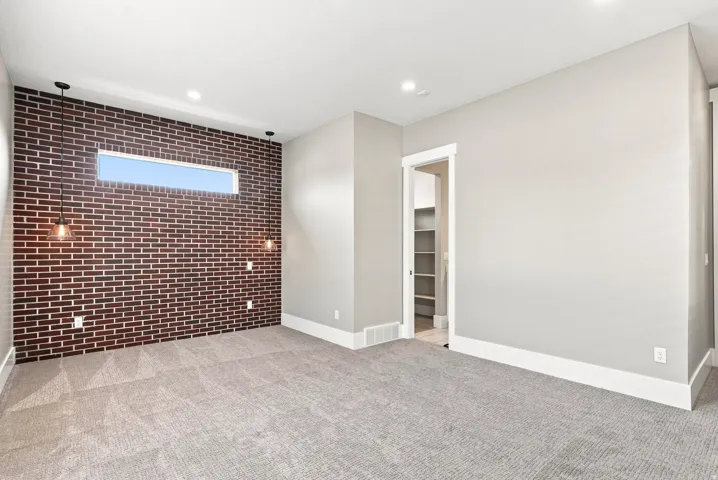 Bedroom 2 on main level, Accent brick wall with a horizontal window, complemented by dual pendant lights and recessed ceiling lighting