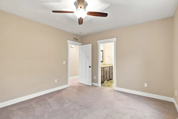 Carpeted room featuring a ceiling fan with integrated lighting, two panel doors, and neutral wall tones