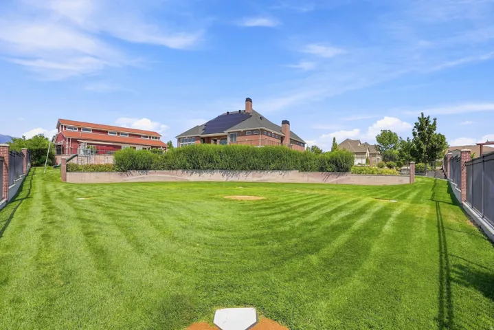 Wiffle ball field featuring a brick retaining wall, and mature perimeter landscaping