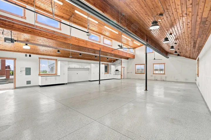 Spacious interior featuring a high vaulted wood-plank ceiling, exposed structural beams, and a light-colored epoxy floor
