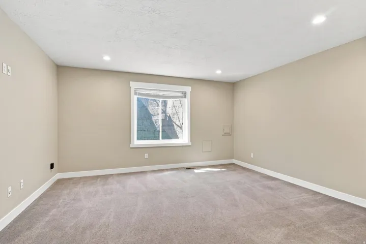 Carpeted room with recessed lighting, neutral wall paint, white trim, and a window featuring a white frame