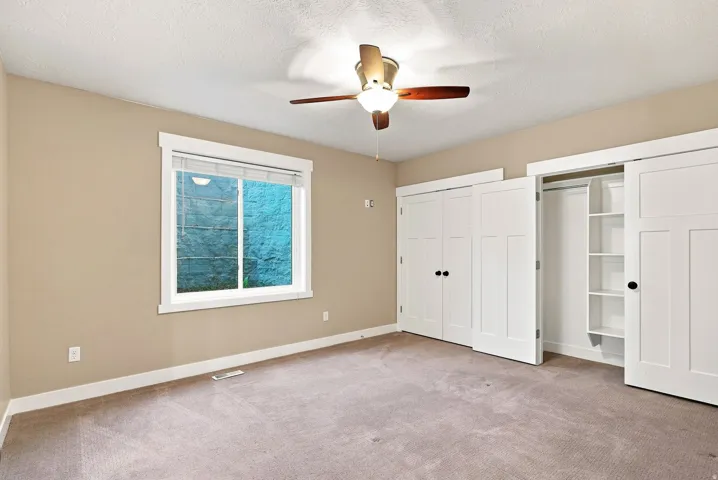 Room featuring neutral-toned walls, a white-framed window, and a ceiling fan with integrated lighting